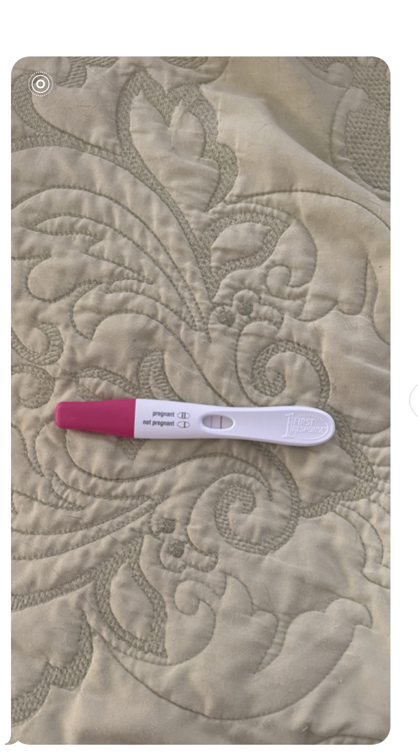 Positive First Response pregnancy test resting on a quilt